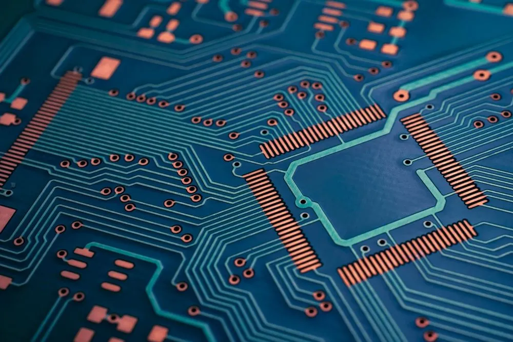 Macro photograph of a populated printed circuit board showing surface-mount pads, vias, and routed copper traces